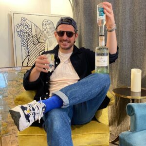 Fabien tenant une bouteille de Gin, une bouteille de Tonic et un verre de Gin Tonic